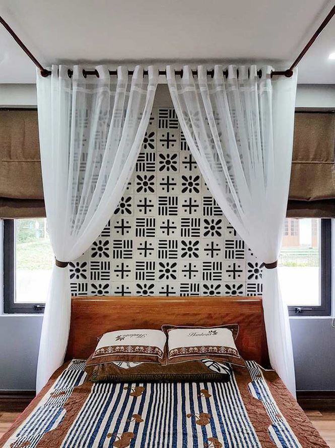 Phòng ngủ được thiết kế với gạch bông thông gió. Giường gỗ có kiểu dáng đơn giản cùng  họa tiết nổi bật của chăn, gối kết hợp sự nhẹ nhàng từ rèm cửa trắng  ​đem đến cảm giác thoải mái, dễ chịu.