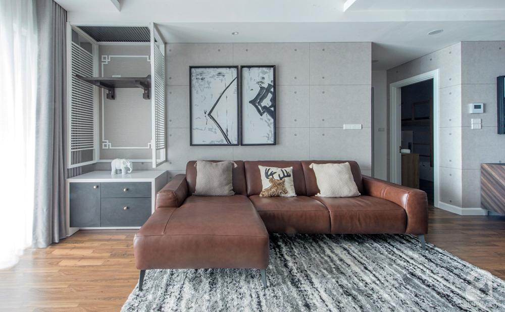 Phòng khách được thiết kế đơn giản với giấy dán tường màu ghi.  Sofa da trở thành điểm nhấn sang trọng