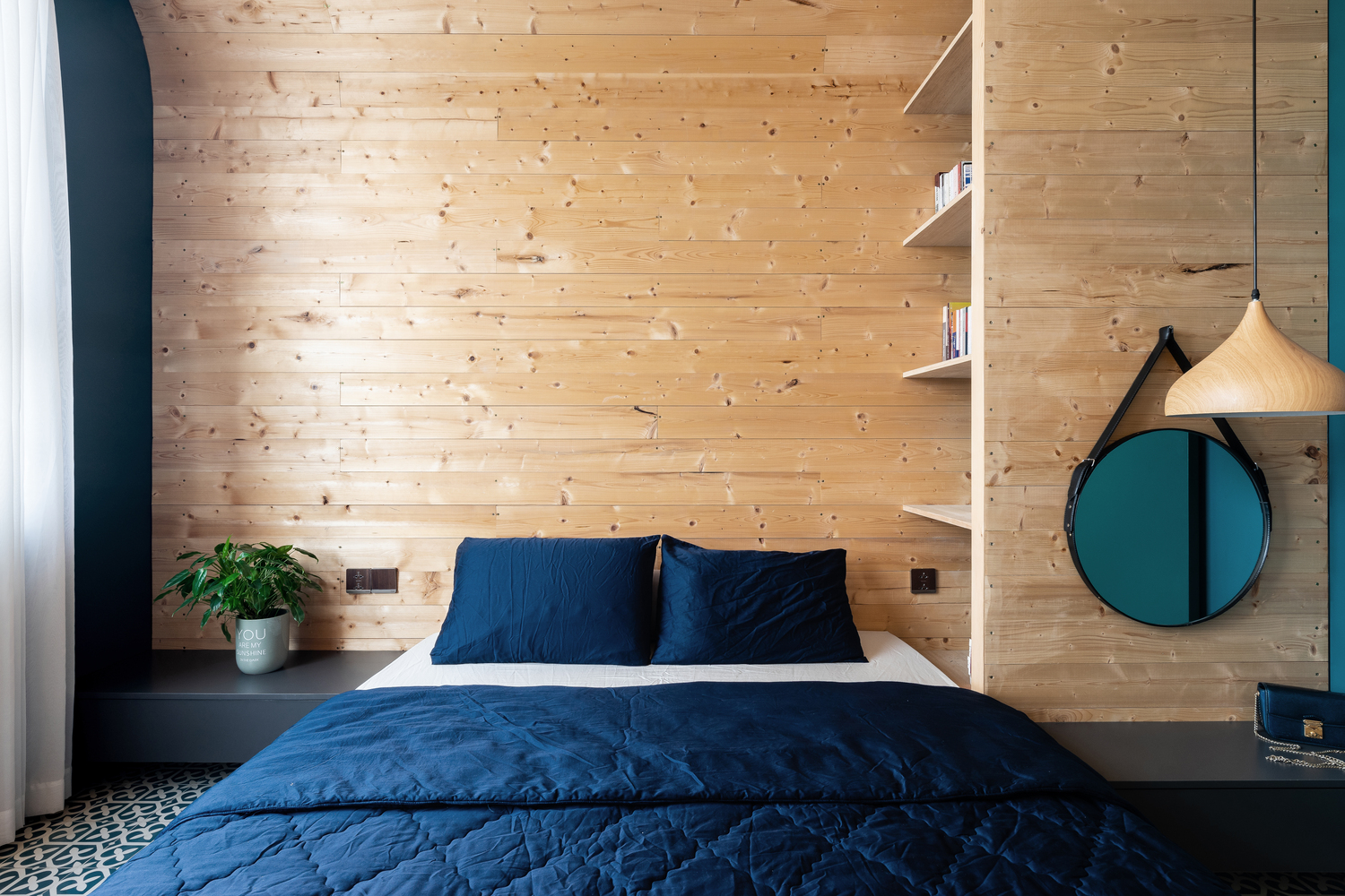 Phòng ngủ được thiết kế theo phong cách tối giản với điểm nhấn là gương tròn và đèn thả
